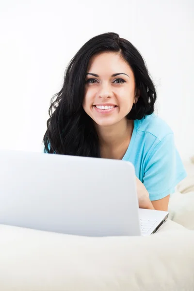 Beautiful woman with computer lying on sofa at home surfing — Stock Photo, Image