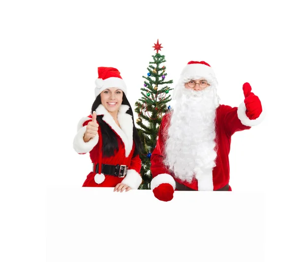 Santa claus en Kerstmis meisje houdt wit bord duim opdagen Stockfoto