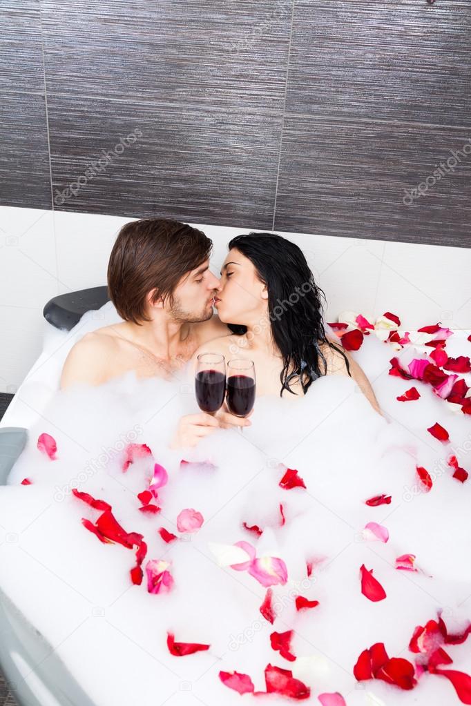 Couple kissing in jacuzzi drink wine