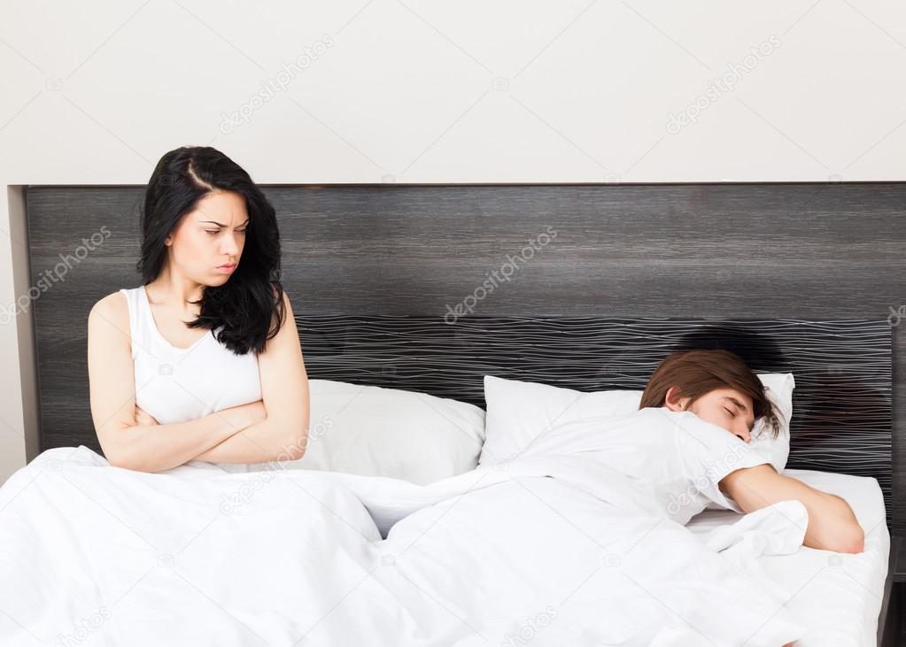 Unhappy separate couple lying in a bed