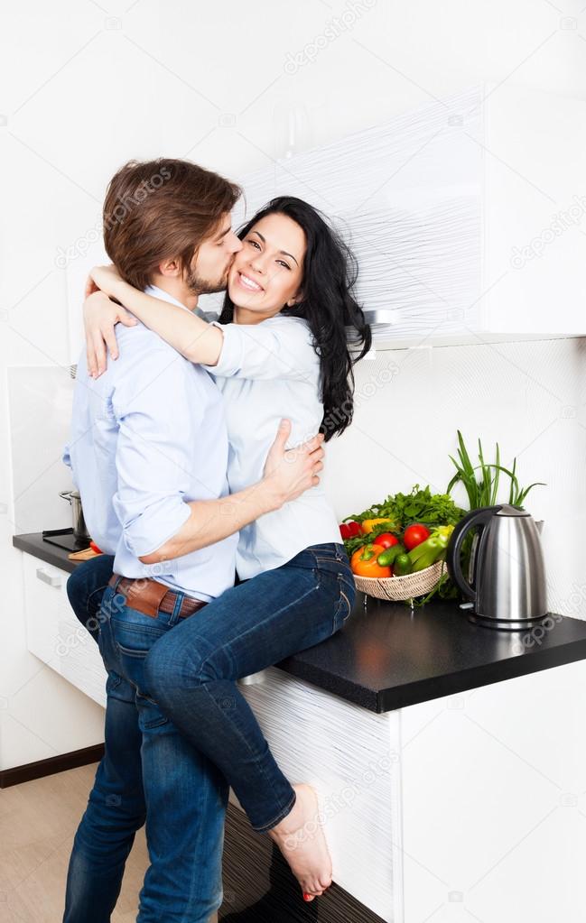 Couple kissing at their kitchen Stock Photo by ©mast3r 31738303