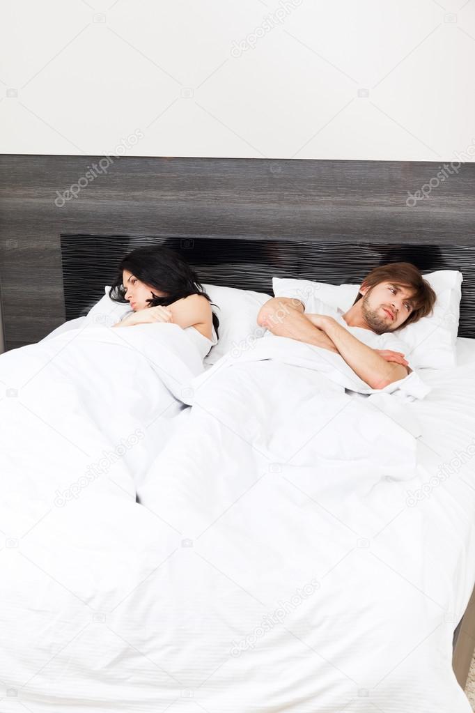 Unhappy separate couple lying in a bed