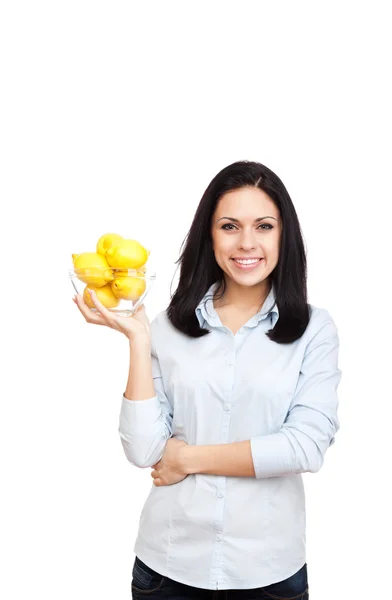 Mujer joven sostiene un tazón lleno de limones — Foto de Stock