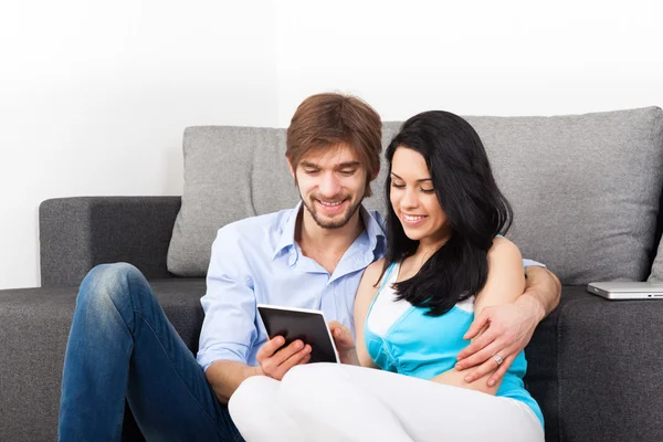 Jeune couple assis sur un canapé — Photo