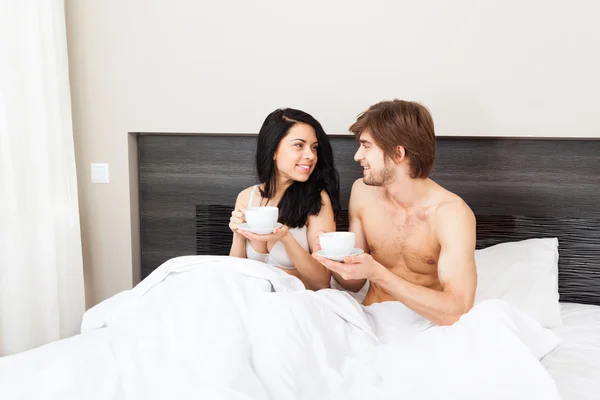 Jovem casal beber café na cama — Fotografia de Stock