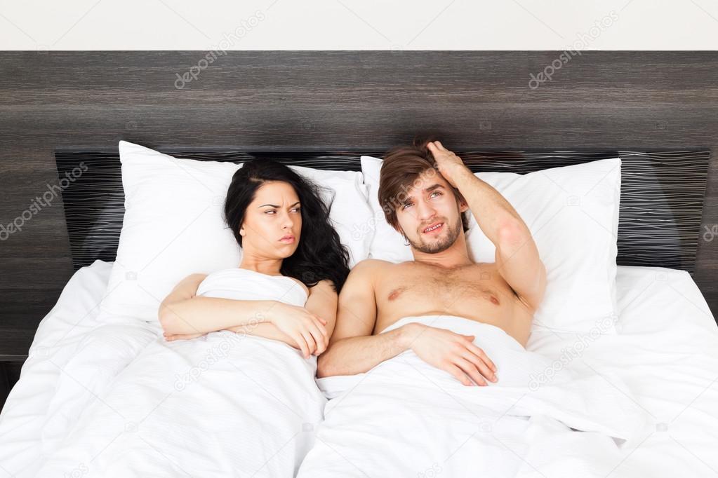 Unhappy separate couple lying in a bed