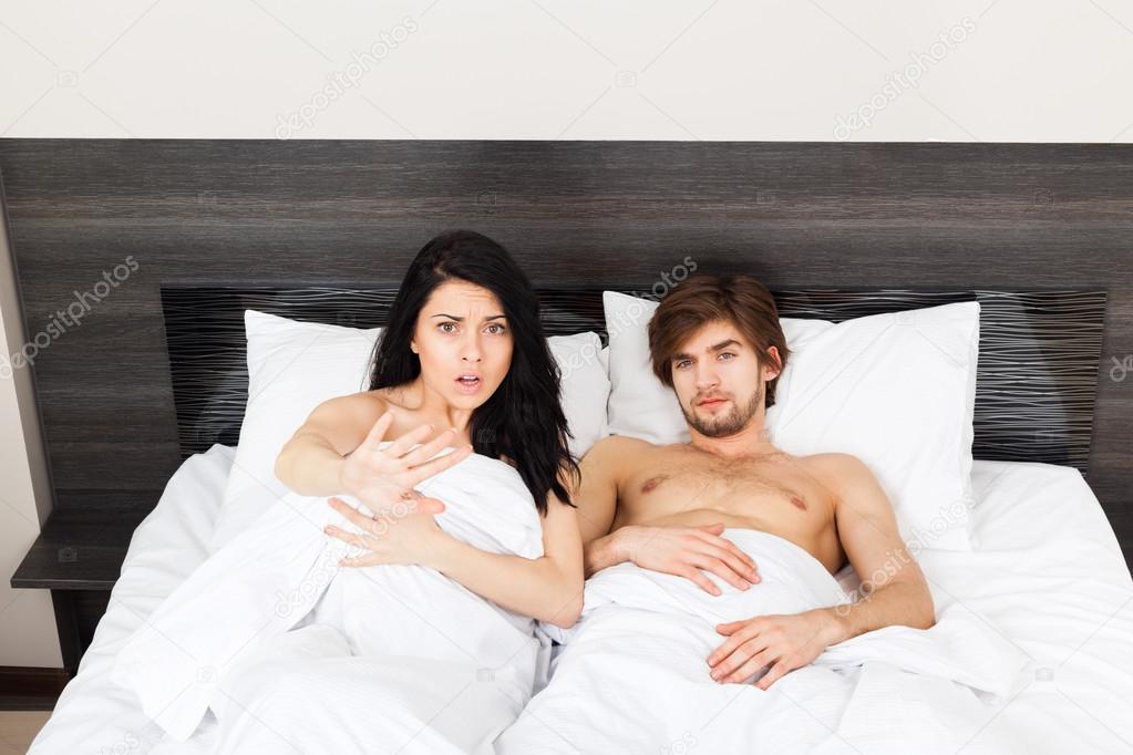 Unhappy surprise couple lying in a bed