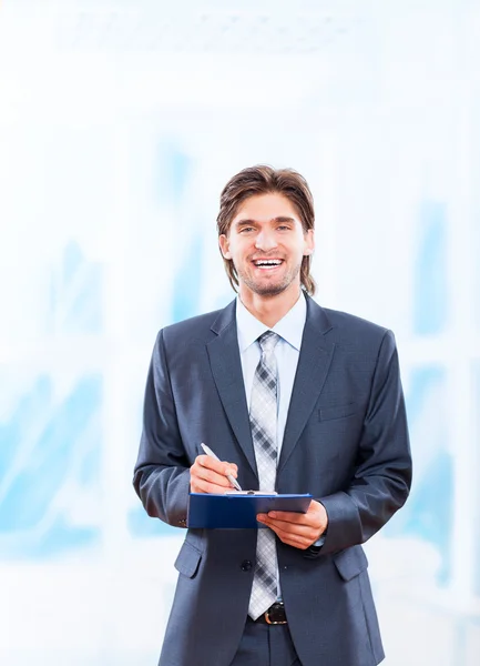 Hombre de negocios con portapapeles en brillante oficina azul — Foto de Stock