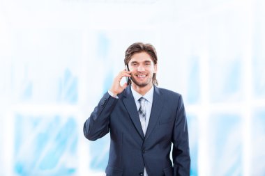 parlak mavi ofis cep telefonunda konuşan işadamı