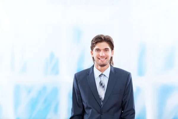 Genç iş adamı gülümseme parlak mavi ofis — Stok fotoğraf