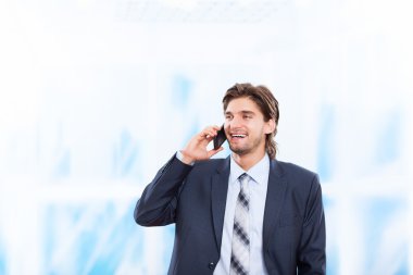 parlak mavi ofis cep telefonunda konuşan işadamı