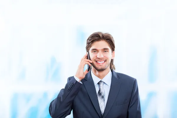 Businessman talking on mobile phone in bright blue office — Stock Photo, Image