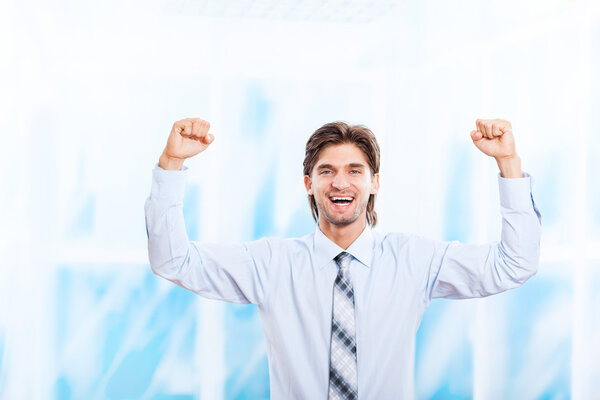 Successful excited business man happy smile hold fists up gesture in bright blue office