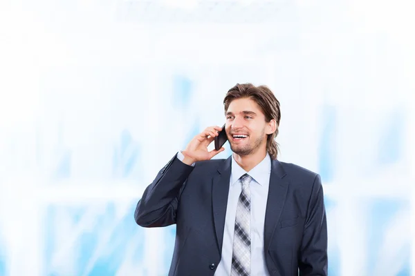 明るい青色のオフィスでの携帯電話で話している実業家 — ストック写真