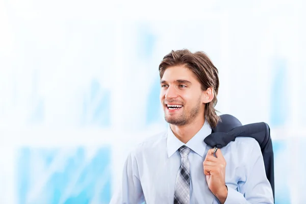 Junger Geschäftsmann lächelt in hellblauem Büro — Stockfoto