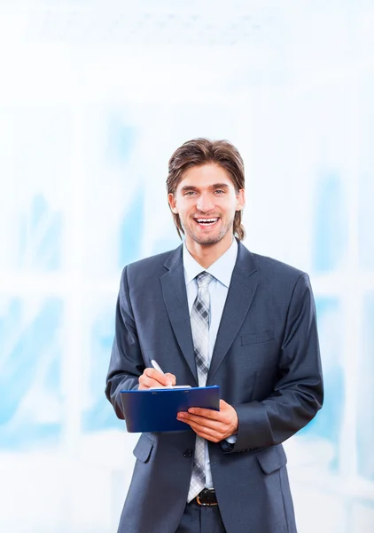 Business man with clipboard in bright blue office — Stock Photo, Image