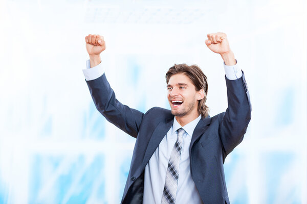 Successful excited business man happy smile hold fists up gesture in bright blue office