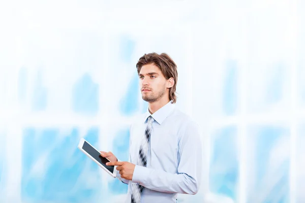 Obchodní muž pomocí panelu tabletu v zářivě modré úřadu, dotykové obrazovky mladý podnikatel — Stock fotografie