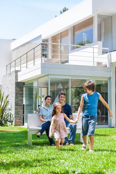 Familia frente a gran casa moderna — Foto de Stock