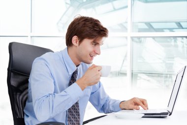 işadamı kahve içmek ve dizüstü bilgisayar kullanarak