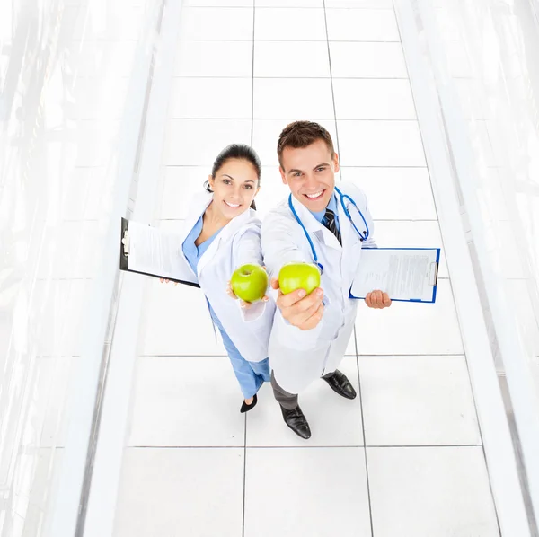 Doctors hold green fresh apples — Stock Photo, Image
