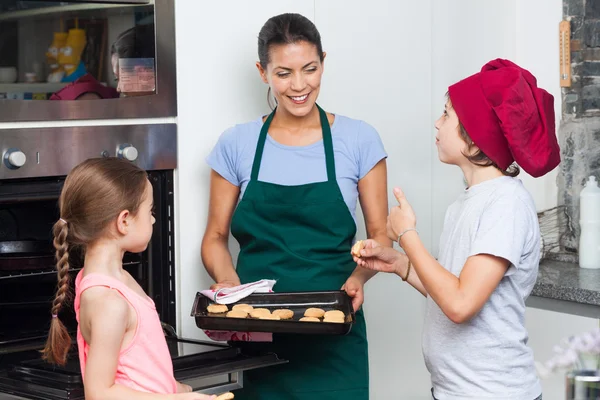 Anya és a gyermekek véve a cookie-kat a sütőből — Stock Fotó