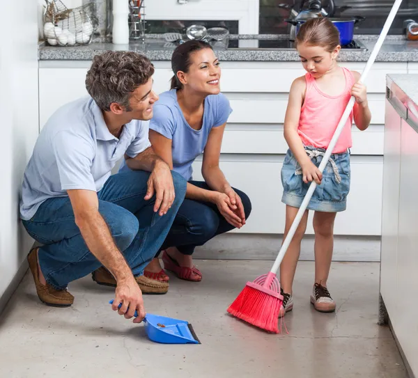 Father, mother and daughter sweeping floor — Stock Photo, Image