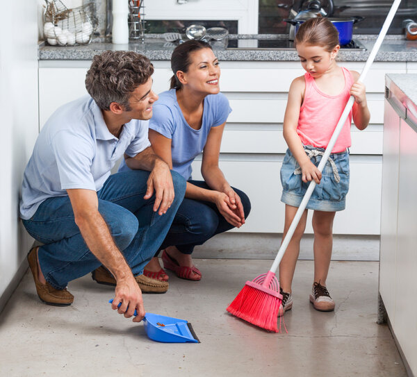 Father, mother and daughter sweeping floor