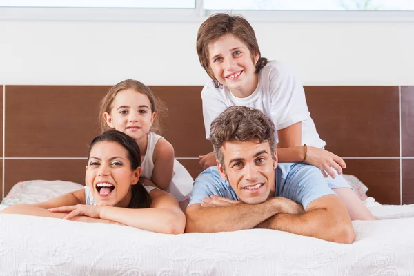 Familia acostada en la cama en el dormitorio — Foto de Stock