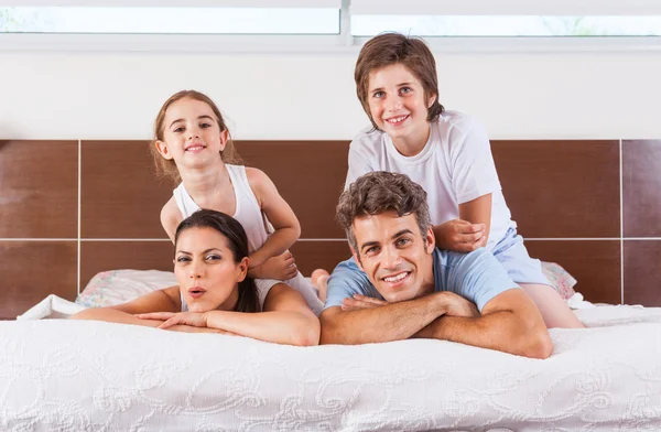 Familia acostada en la cama en el dormitorio — Foto de Stock