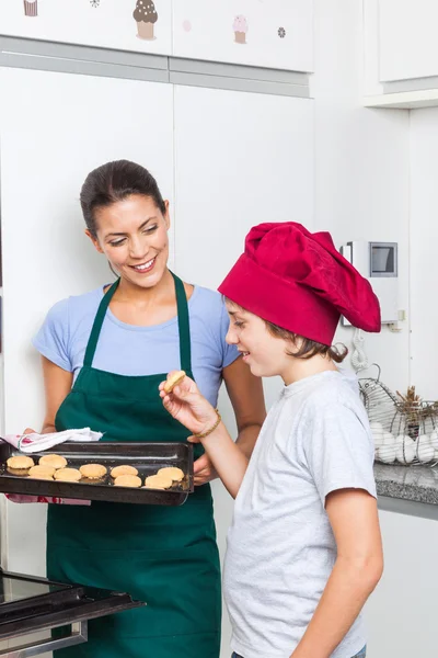 Mother and son taking cookies from oven — Stock Photo, Image