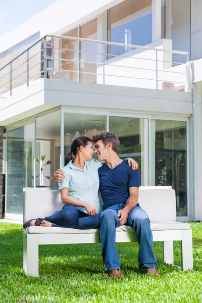 Casal sentado na frente de uma grande casa moderna — Fotografia de Stock