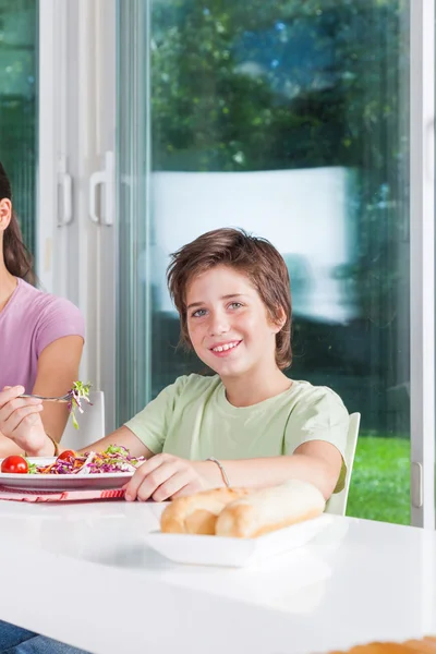 Junge isst Salat am Tisch — Stockfoto