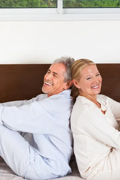 Seniorenpaar sitzt auf Bett — Stockfoto