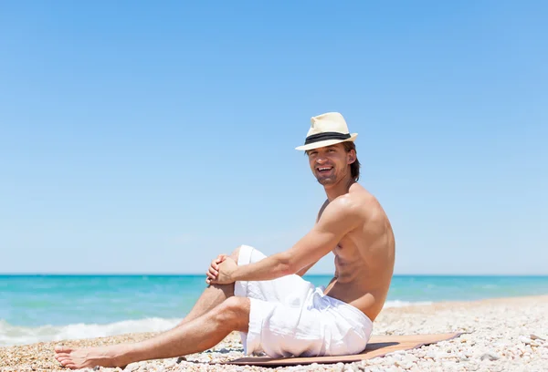 Uomo seduto sulla spiaggia — Foto Stock