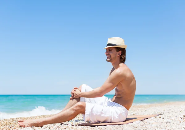 Uomo seduto sulla spiaggia — Foto Stock