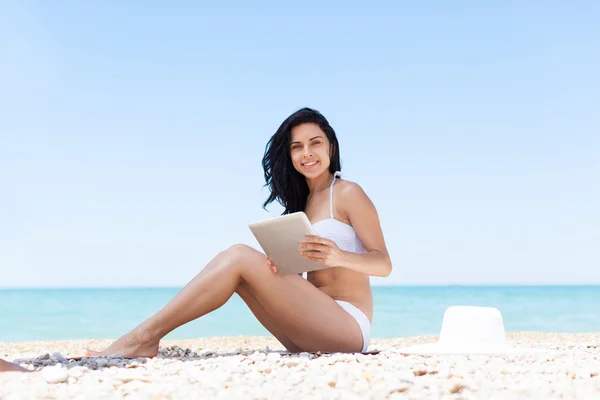 Vrouw die tablet pc gebruikt op strand — Stockfoto