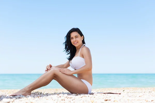 Woman applying lotion on leg — Stock Photo, Image