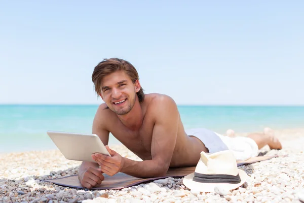 Man met tablet pc op strand — Stockfoto