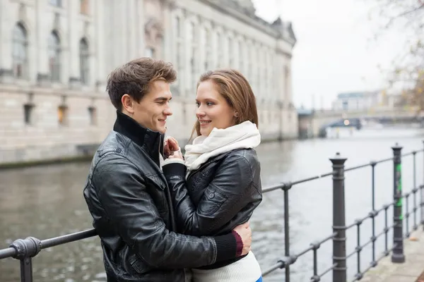 Romantisches Paar in Jacken, das sich an der Reling umarmt — Stockfoto