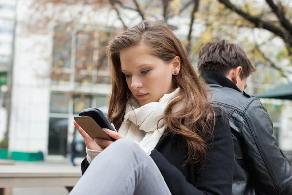 Frau benutzt Handy mit Freund im Hintergrund — Stockfoto