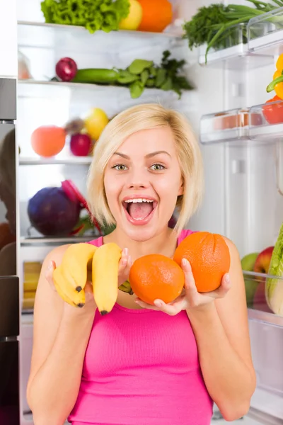 Mulher segura banana e laranja — Fotografia de Stock