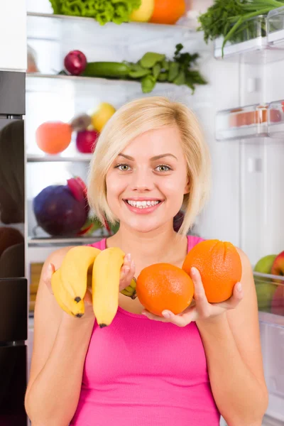 Woman holds banana and orange — Stock Photo, Image