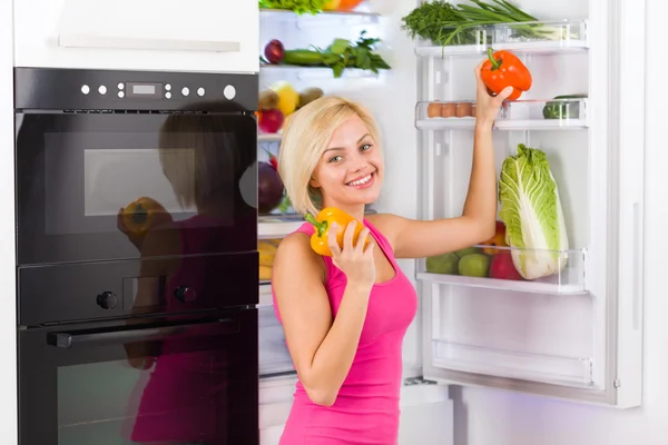 Meisje houdt rode en gele paprika 's — Stockfoto