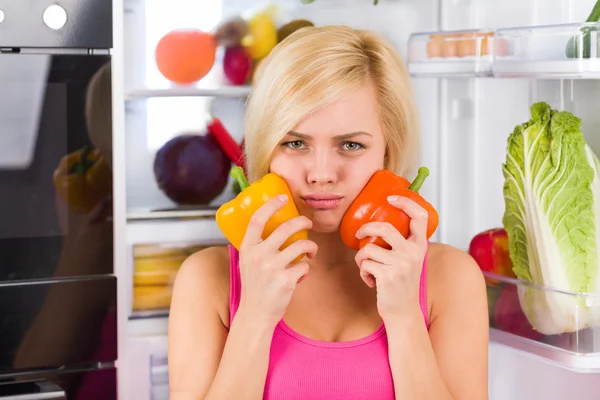 Meisje houdt rode en gele paprika 's — Stockfoto