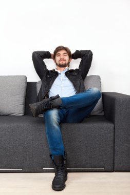 Oturma odasındaki kanepede oturan adam.