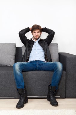 Oturma odasındaki kanepede oturan adam.