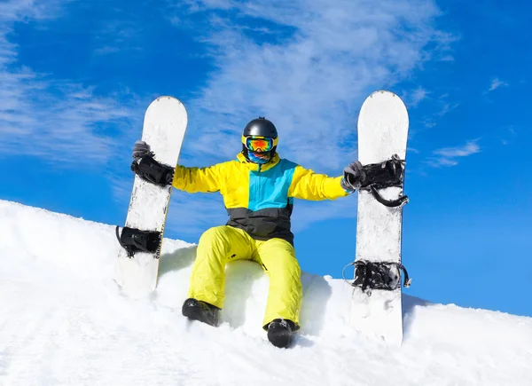 Сноубордист сидит на снежном склоне с сноубордами — стоковое фото