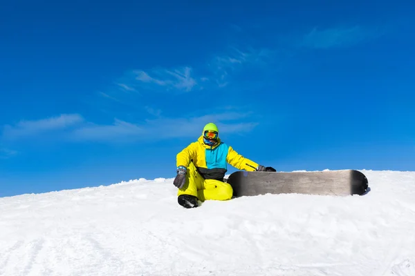 Сноубордист, сидящий на склоне горы — стоковое фото