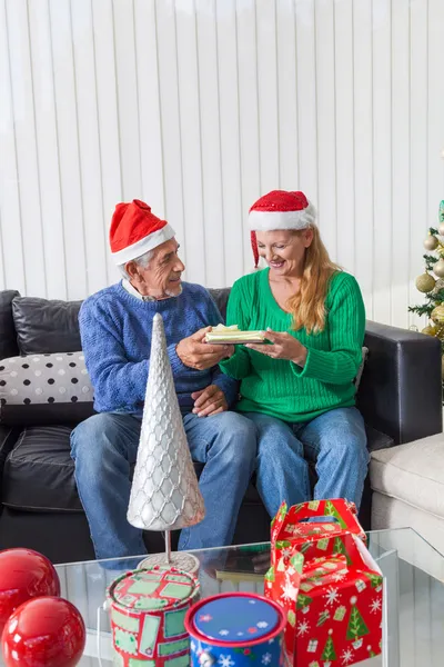 Старшая пара дарит рождественский подарок — стоковое фото